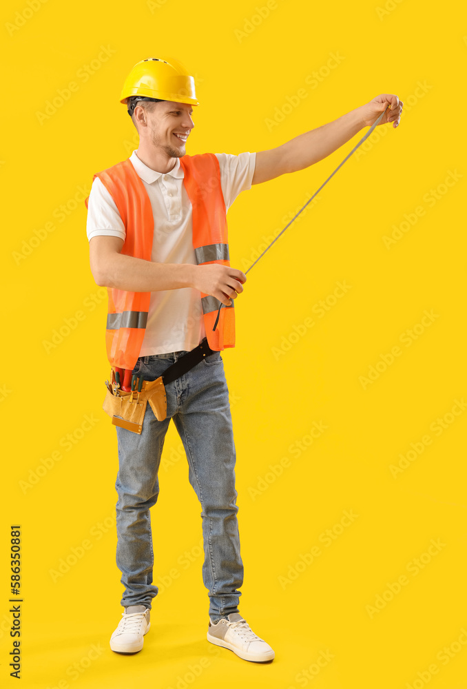 Male worker with tape ruler on yellow background
