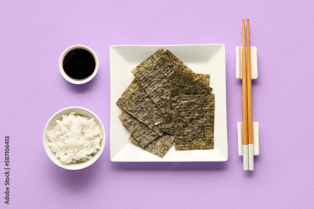 Plate with nori sheets, chopsticks, rice and soy sauce on color background