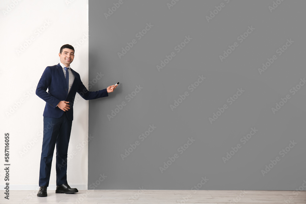 Business consultant with marker near black and white wall