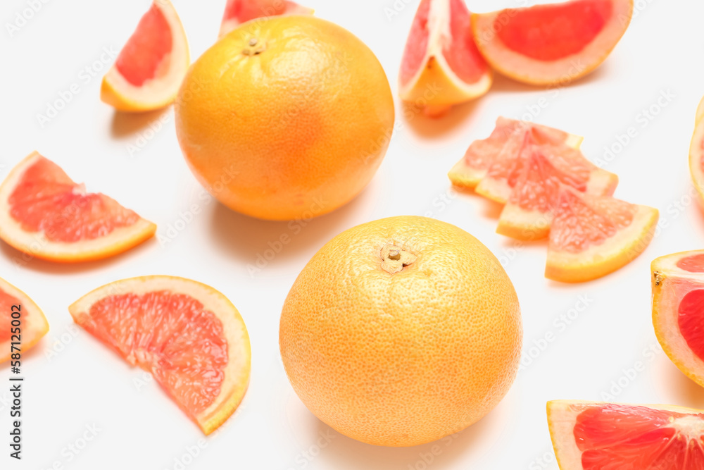 Composition with cut and whole ripe grapefruits on white background, closeup