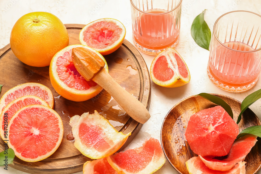 Cut ripe grapefruits, peel and glasses of juice on light background, closeup