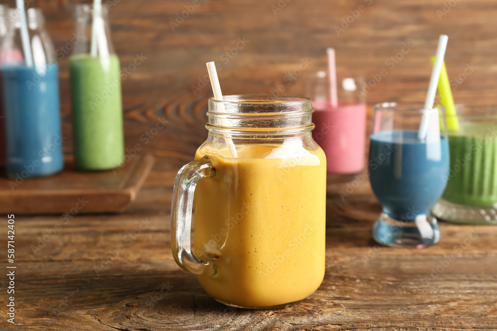 Mason jar of yellow smoothie on wooden table