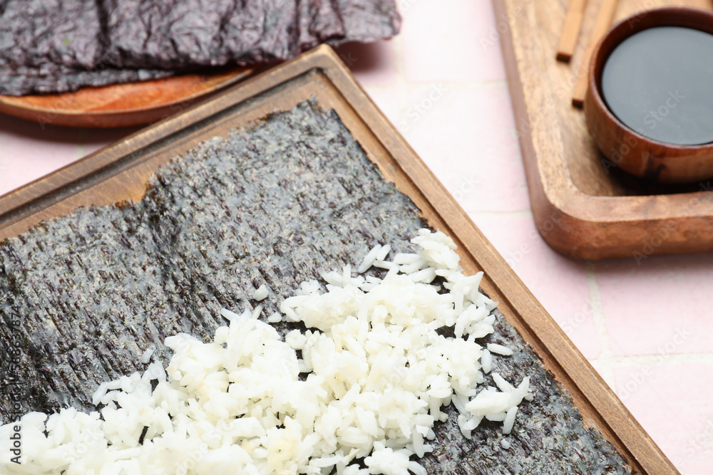 Wooden board of nori with rice on table, closeup