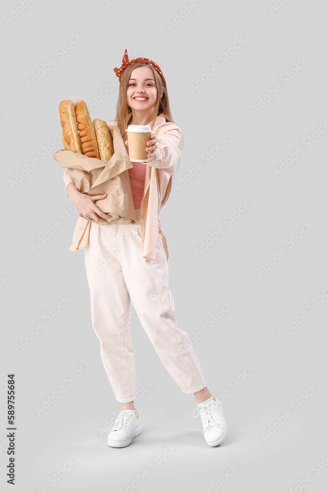 Young woman with fresh baguettes and cup of coffee on grey background