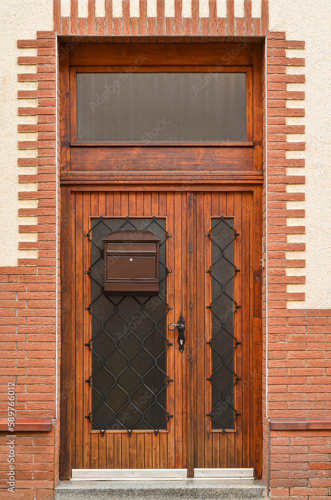 View of brick building with wooden door and mailbox