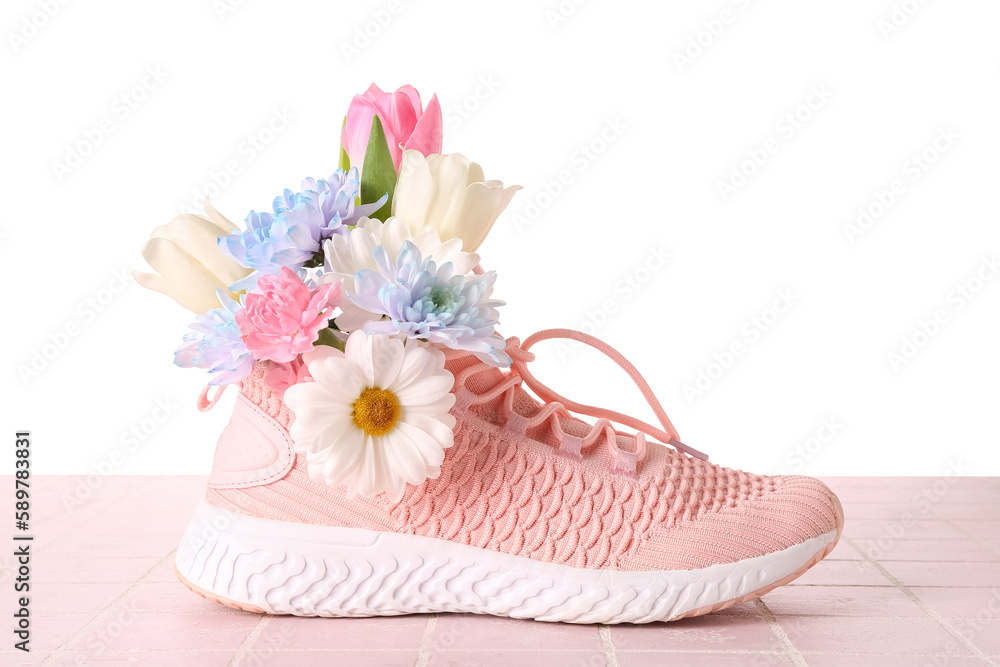 Sneaker with spring flowers on table against white background