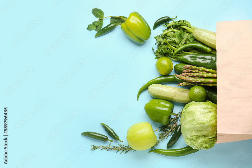 Paper bag with different fresh vegetables and fruits on blue background