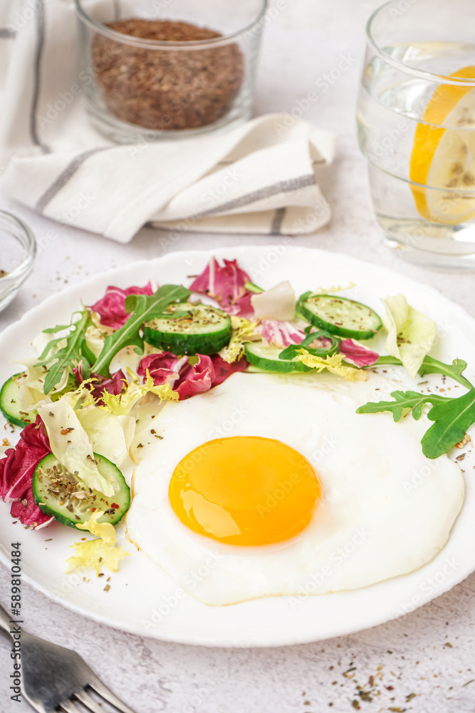 Plate with tasty fried egg and salad on light table