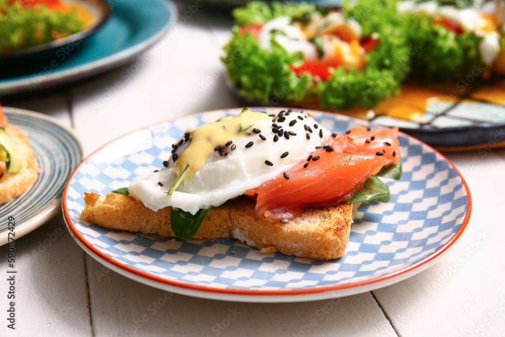 Plate with delicious egg Benedict on white wooden table, closeup