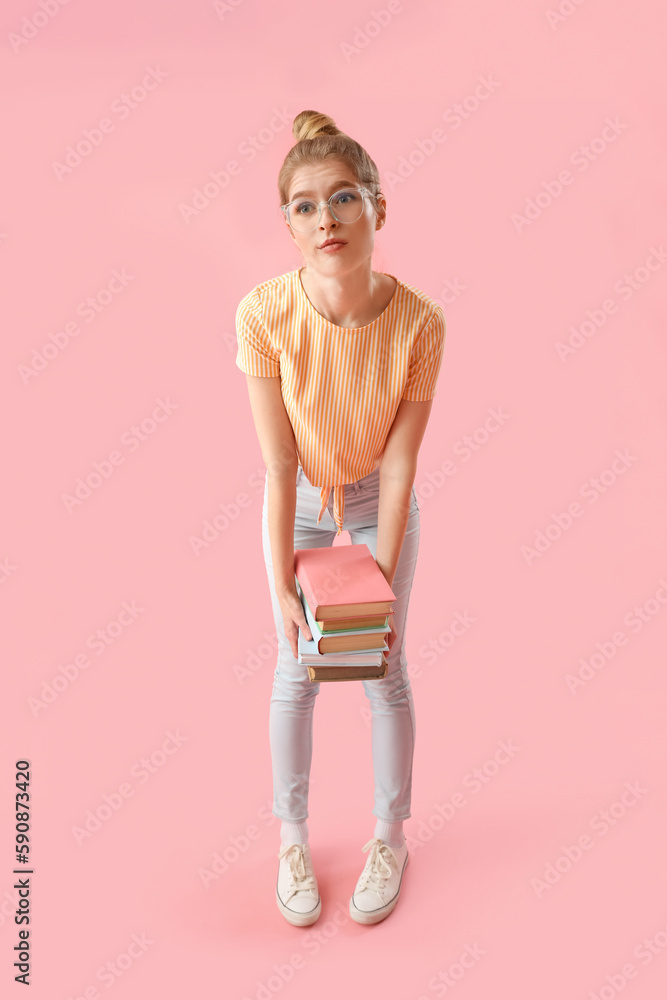 Upset young woman with books on pink background