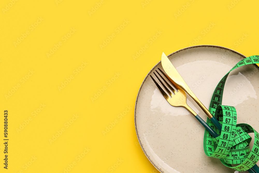 Table setting and measuring tape on yellow background, closeup
