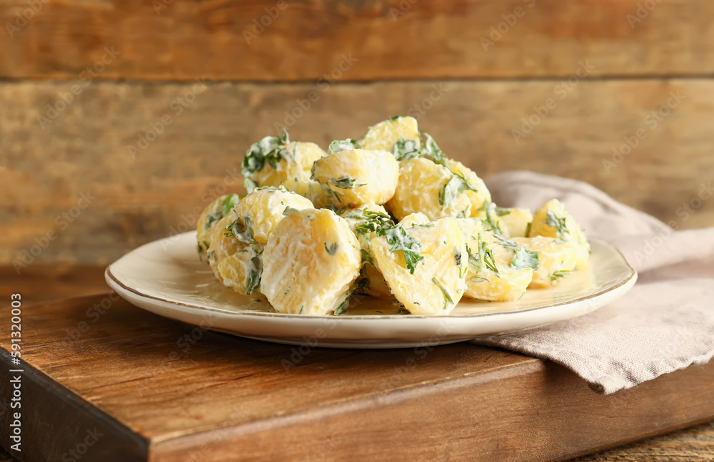Plate of tasty Potato Salad with greens on wooden background