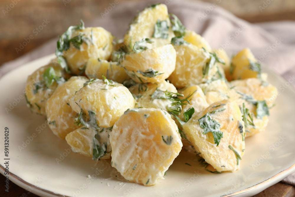 Plate of tasty Potato Salad with greens on table, closeup