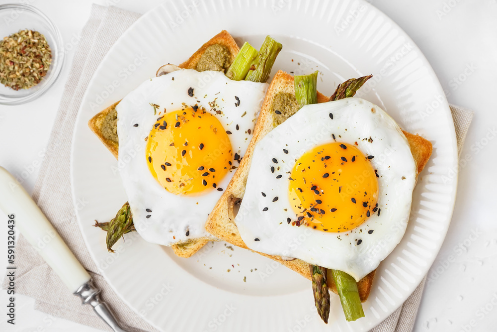 Delicious sandwiches with fried eggs and asparagus on light background