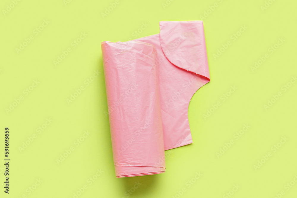 Pink roll of garbage bags on green background