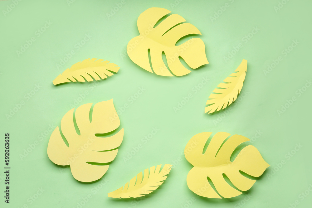 Frame made of yellow paper tropical leaves on green background