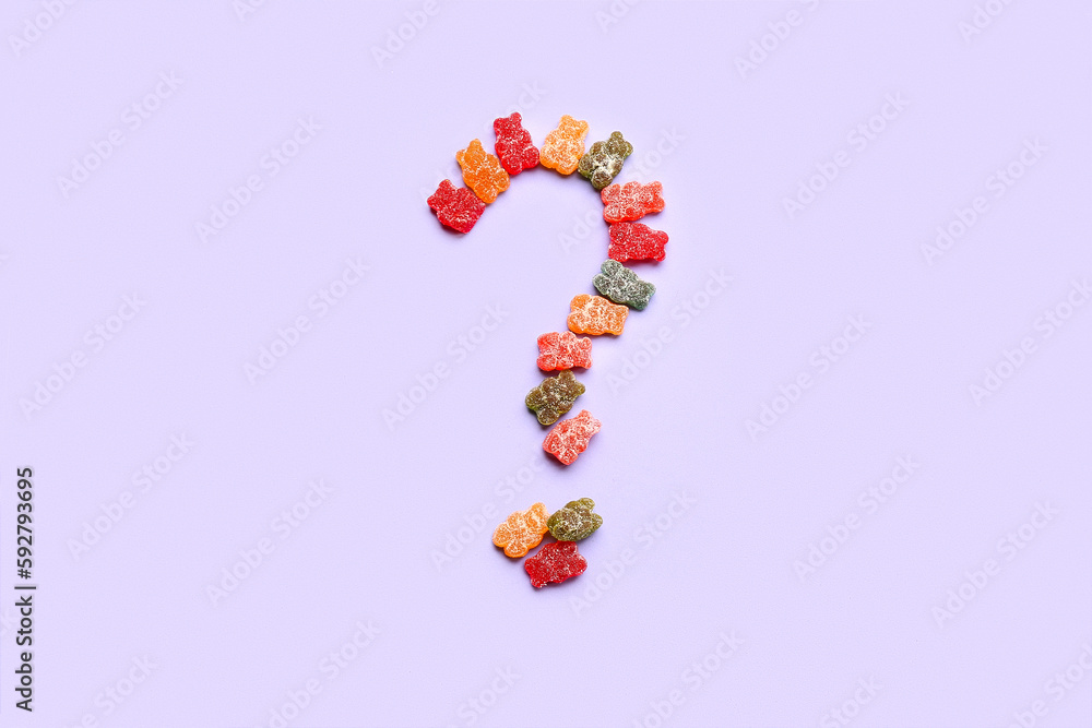Question mark made of gummy bears on lilac background