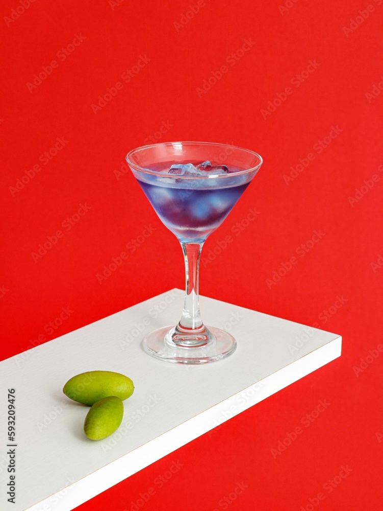 Blue Moon Cocktail glass and olives on white surface isolated on red background