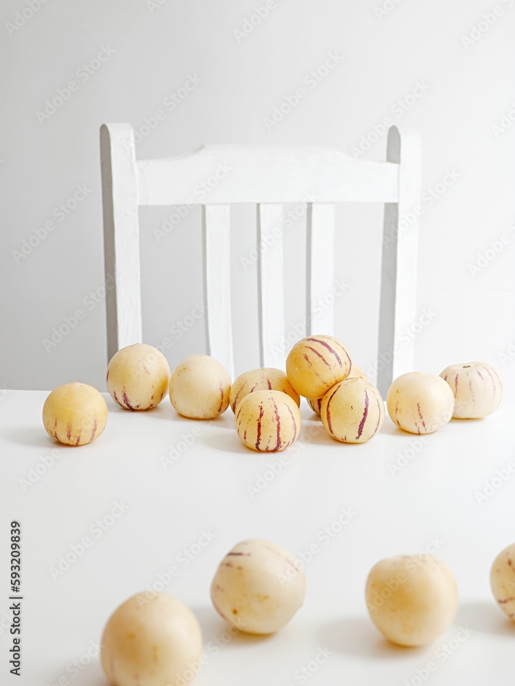 Closeup of delicious yellow pepino melons with red strips on a white table