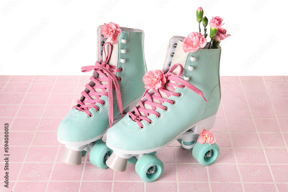 Roller skates with spring flowers on table against white background