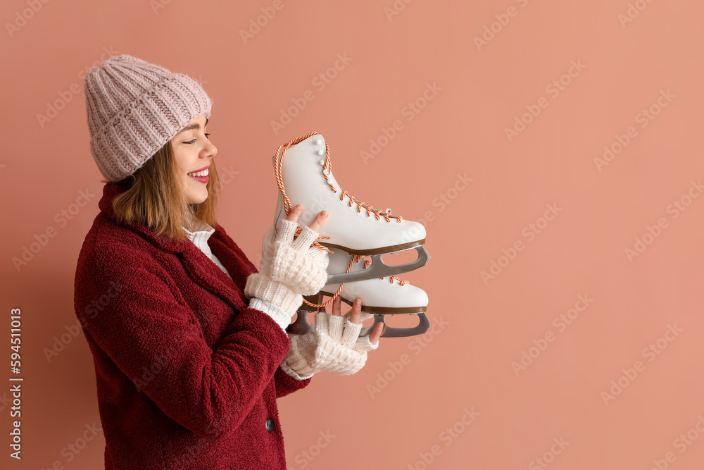 Pretty young woman with ice skates on pink background