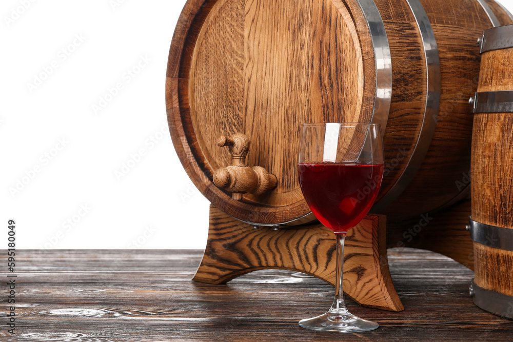 Wooden barrels and glass of wine on table against white background