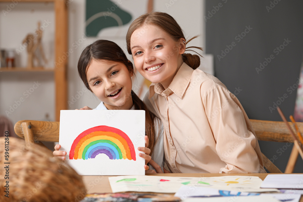 Little girl with painting and her drawing teacher in workshop