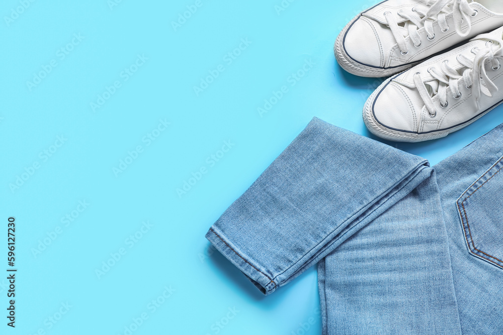 Stylish jeans with sneakers on blue background