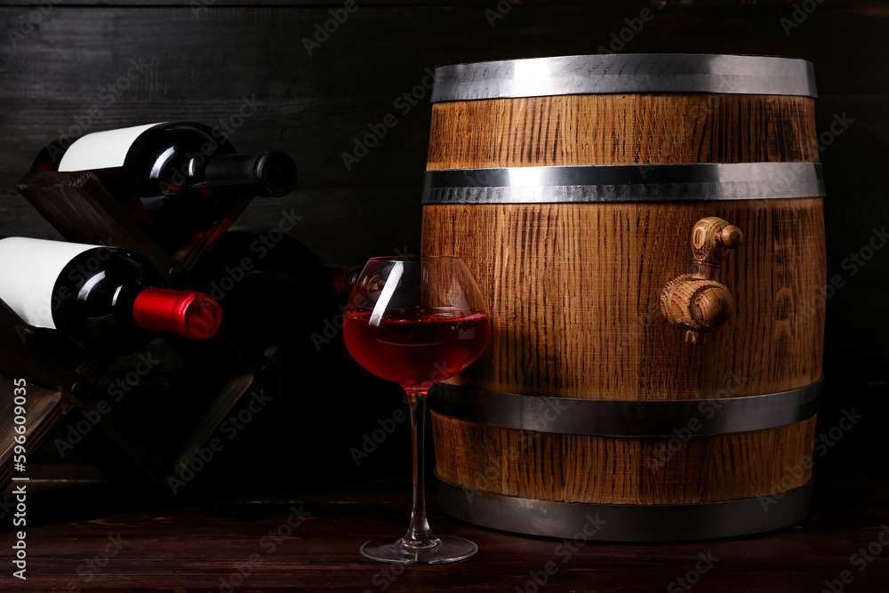 Oak barrel with bottles and glass of wine on dark wooden background