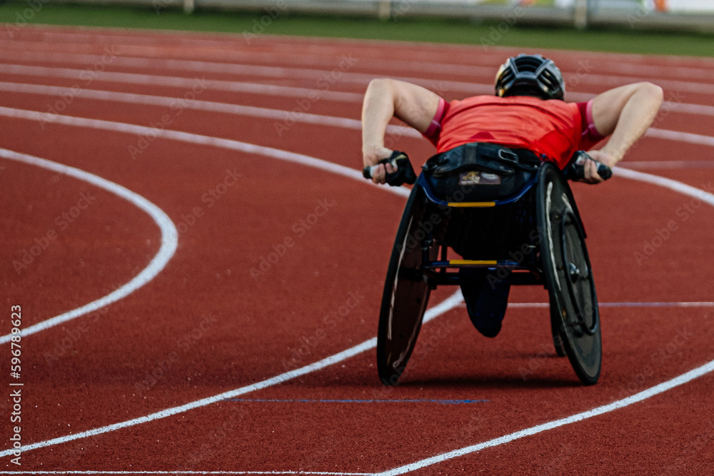 rear view male athlete in racing wheelchair riding on red track stadium, summer para athletics champ