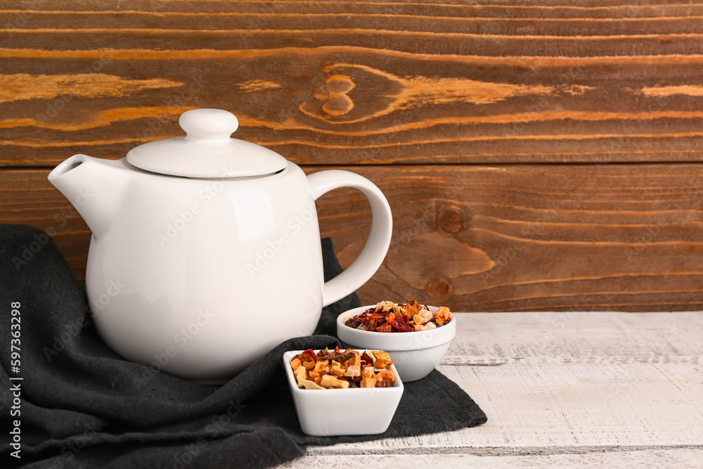 Ceramic teapot and dried fruits on white wooden table