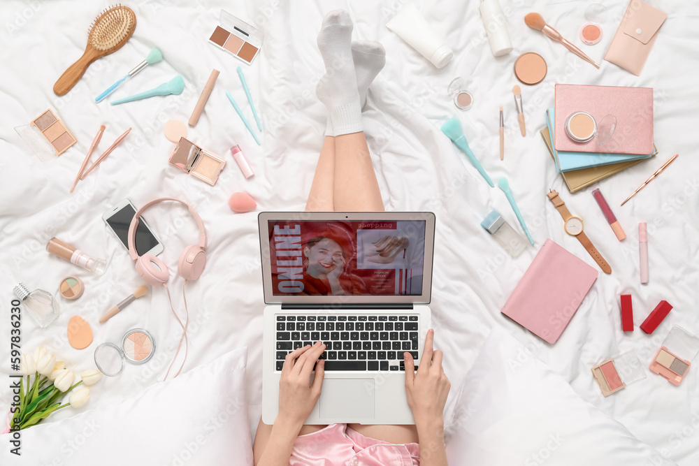 Woman with laptop, makeup products and accessories shopping online on white blanket