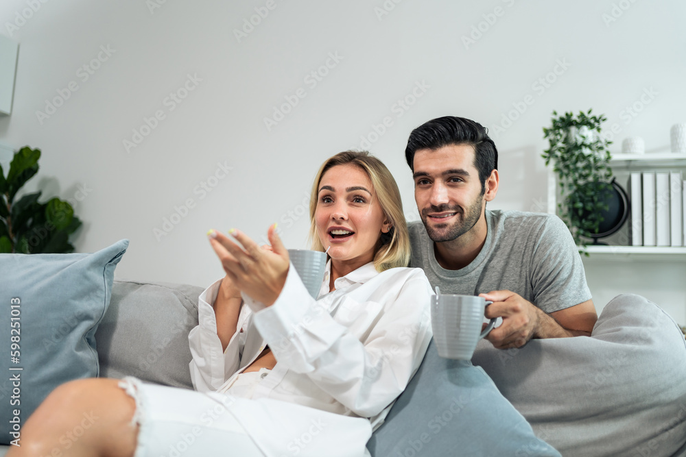 Caucasian young loving couple watch movie together in living room at home. 