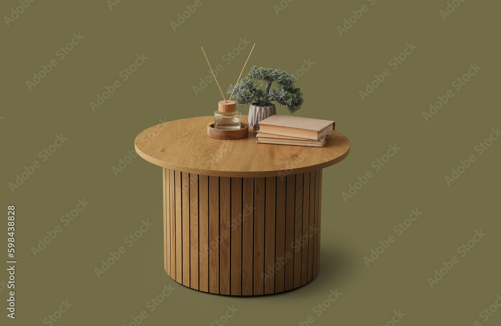 Wooden coffee table with bonsai tree, books and reed diffusers on green background