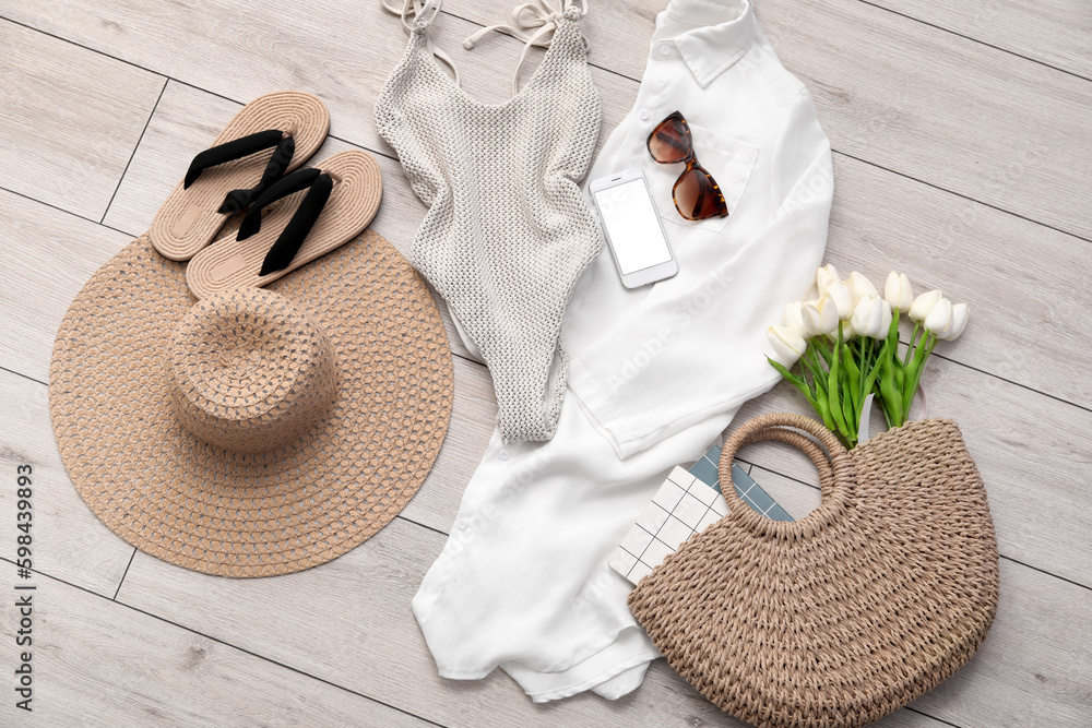 Summer clothes with accessories, mobile phone and tulips on light wooden floor