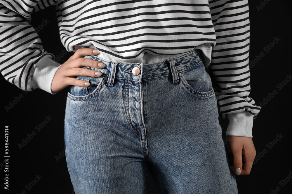 Young woman in stylish jeans on black background, closeup