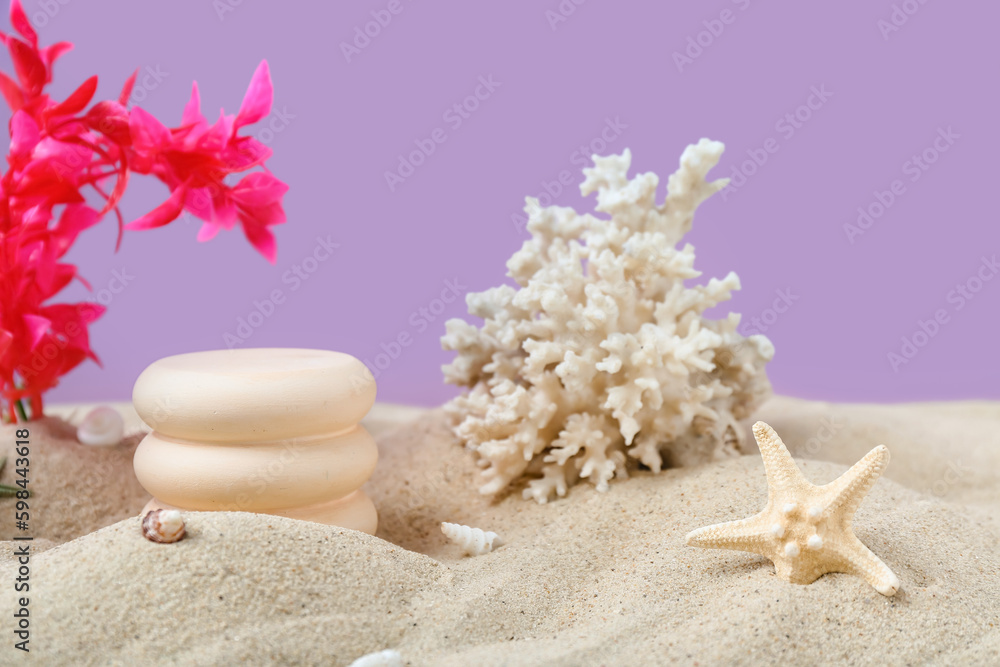 Decorative plaster podiums, seaweed, coral and starfish in sand on purple background
