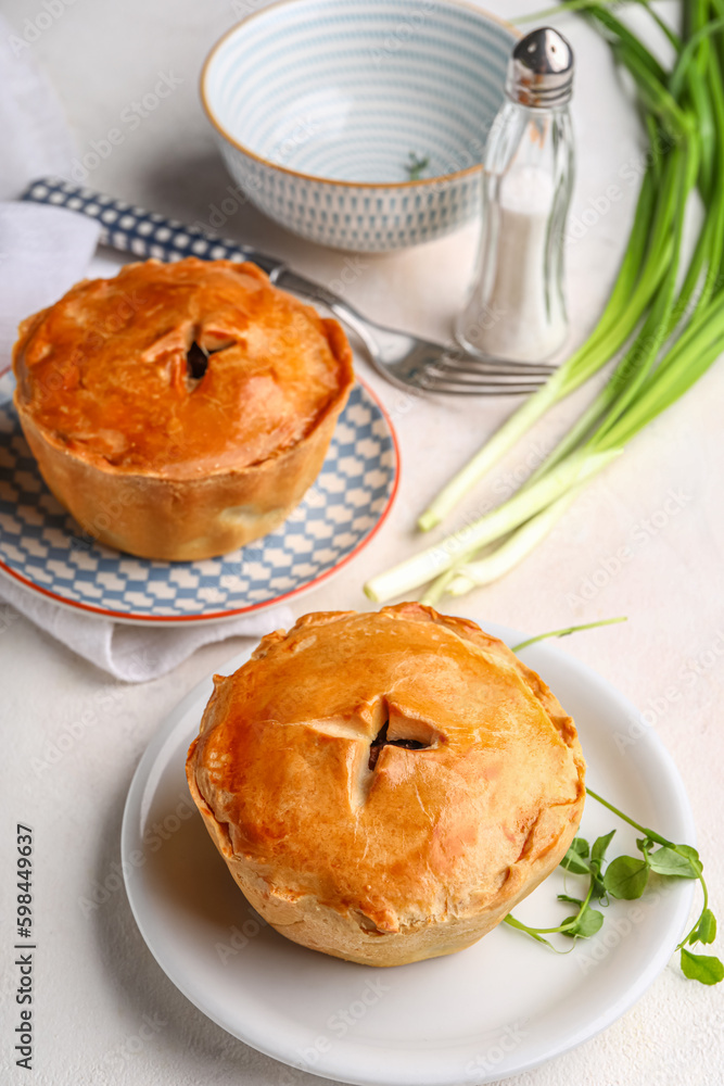 Plates with tasty meat pot pies on light background
