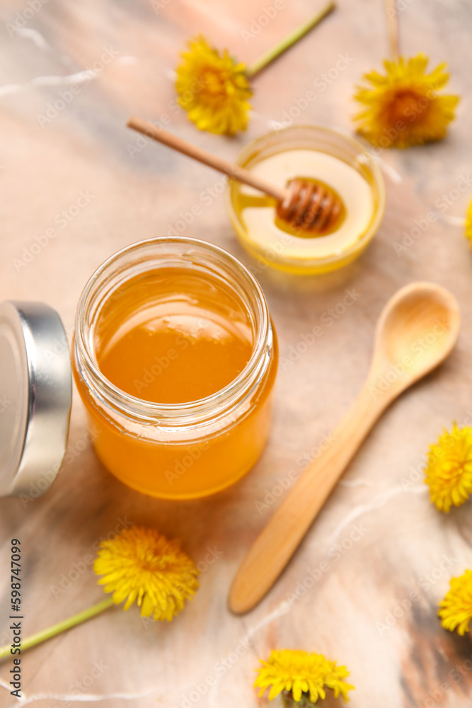 Jar and bowl with dandelion honey on marble background