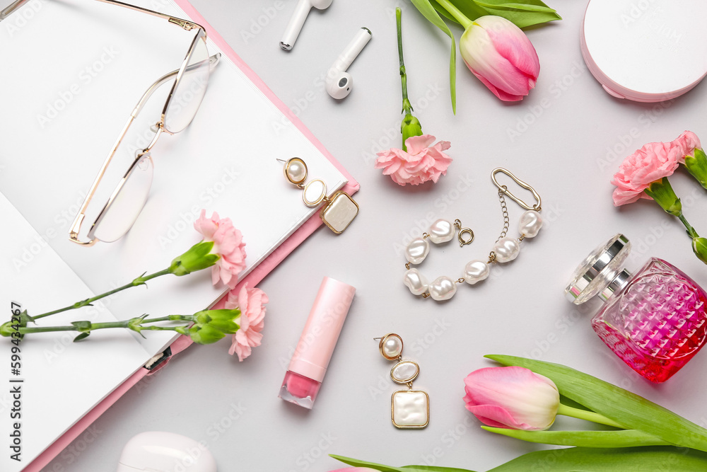 Composition with female accessories, cosmetics, earphones, notebook and spring flowers on light back
