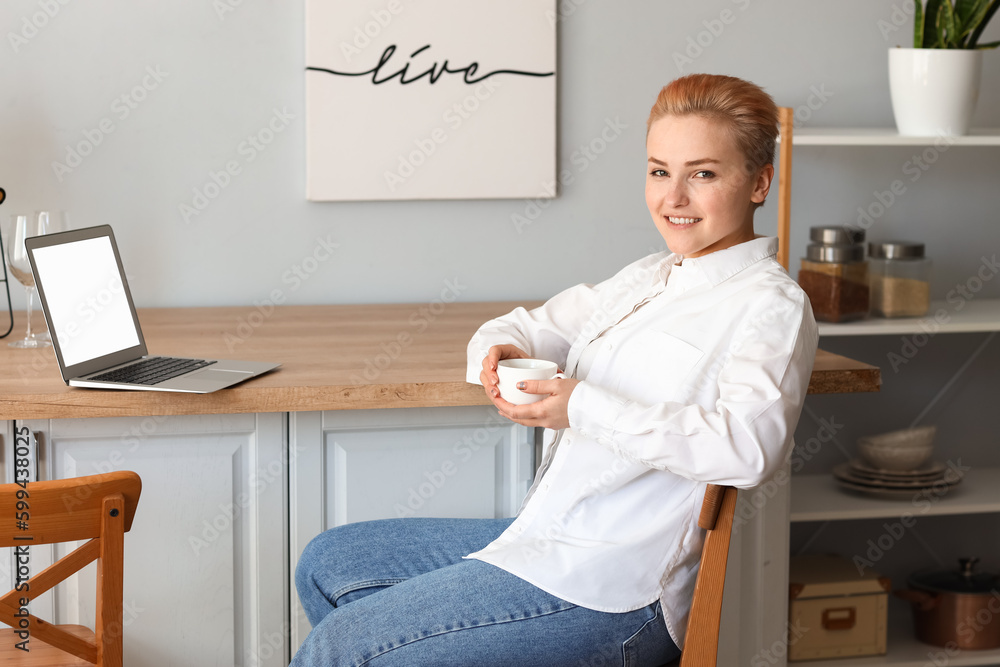 Young woman with cup of coffee in kitchen