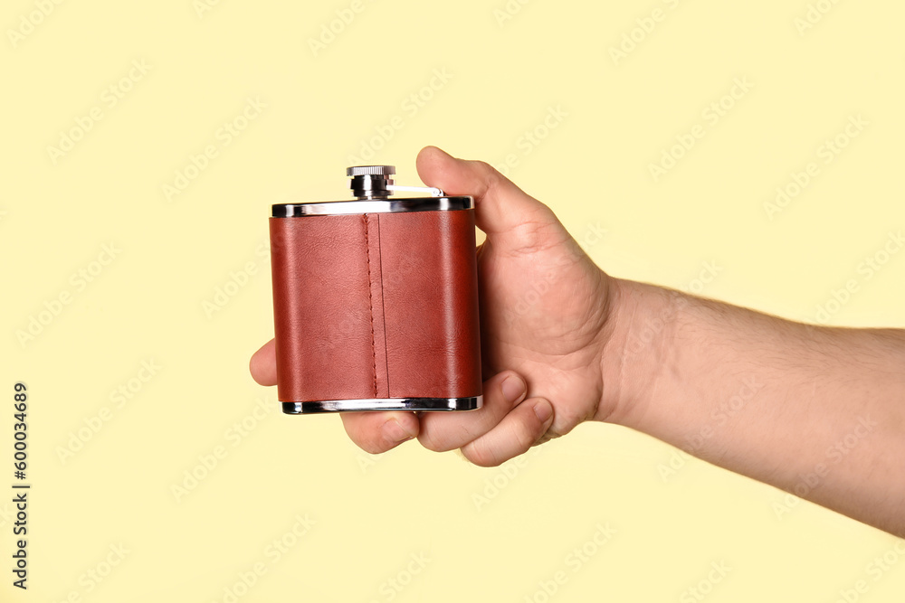 Man holding hip flask on beige background