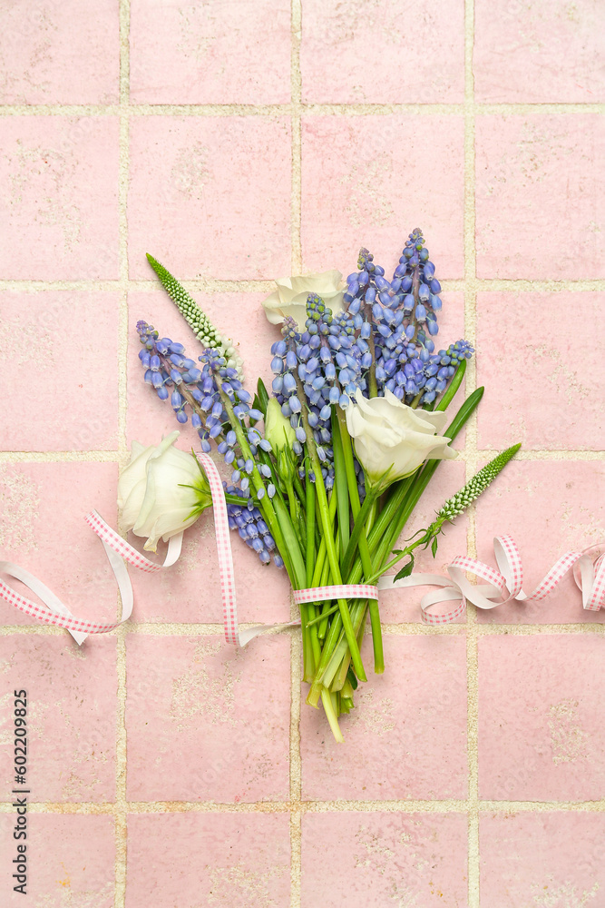 Bouquet of beautiful Muscari and eustoma flowers on pink tiled background