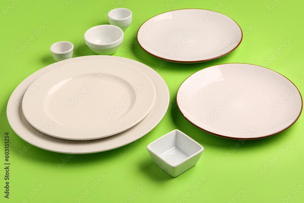 Composition with clean plates and bowls on green background