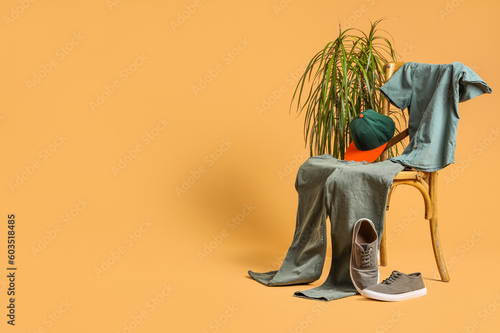 Creative composition with chair, male clothes and shoes on pale orange background