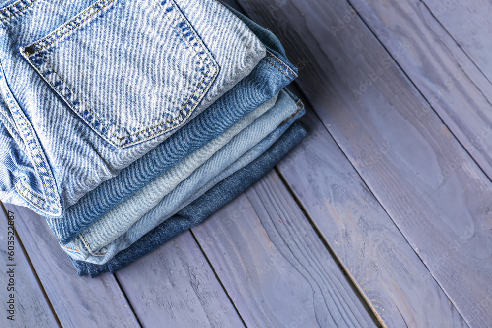 Different folded denim jeans on blue wooden background
