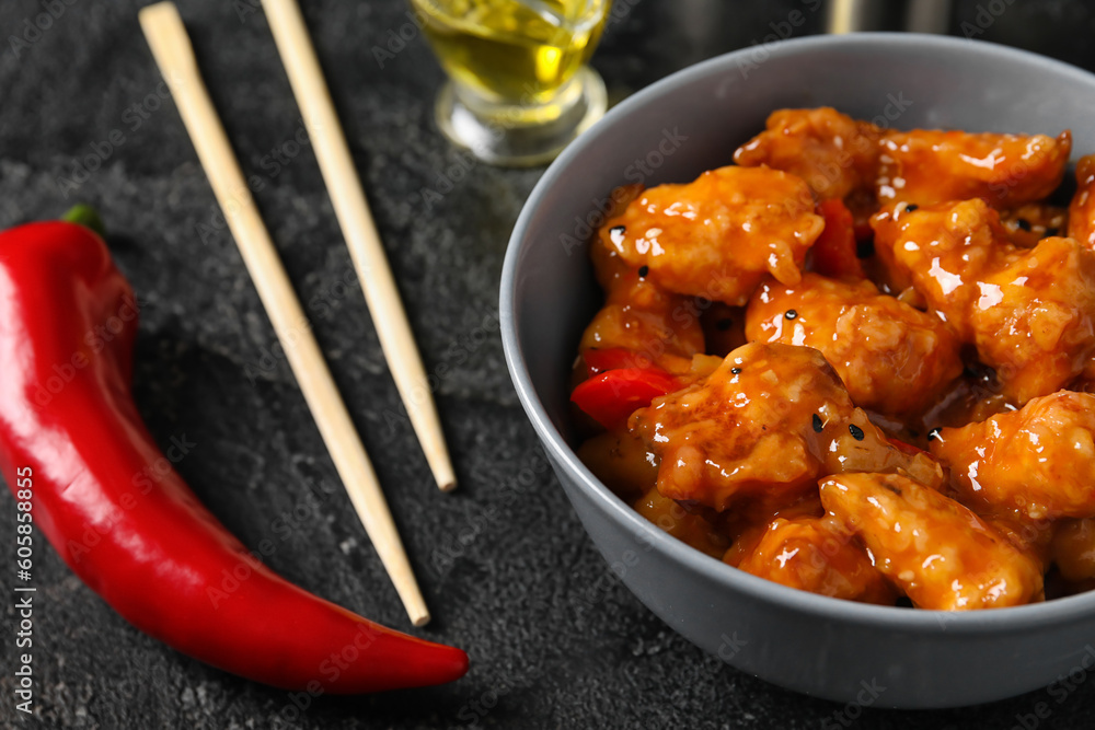 Bowl with tasty sweet and sour chicken on dark background, closeup