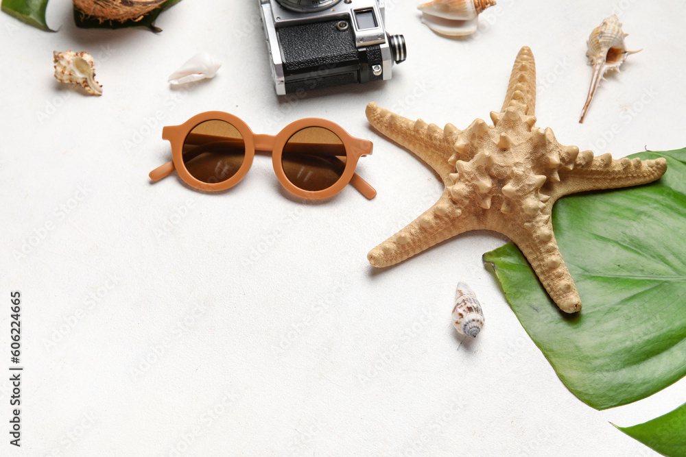Composition with stylish sunglasses, palm leaf, starfish and seashells on light background