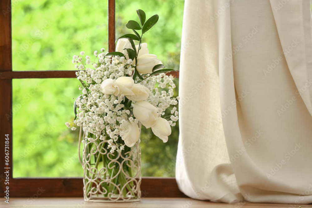 Vase with beautiful tulip and gypsophila flowers on windowsill