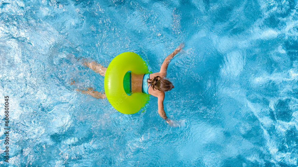 Active young girl in swimming pool aerial top view from above, teenager relaxes and swims on inflata